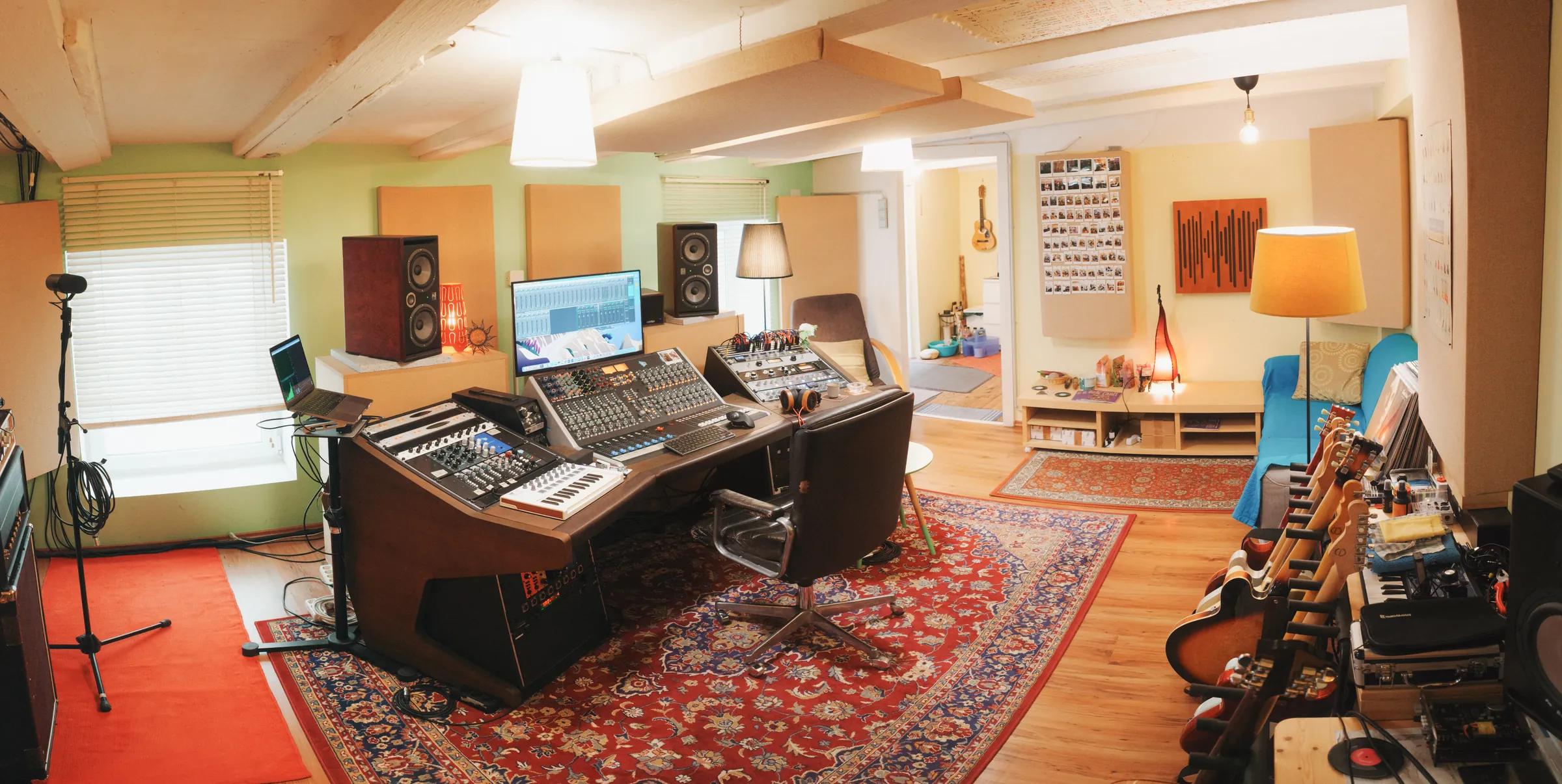 The full width of the control room, with console, monitors, guitars on the wall and a rug.